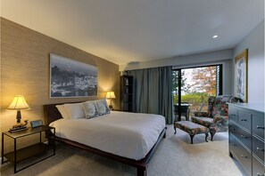 The unit is furnished with a queen-size bed, a charming floral chair, and an attached balcony for a delightful and comfortable stay.