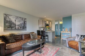 The unit is adorned with a stylish leather couch, a charming breakfast nook, and a kitchen equipped with a microwave for added convenience.
