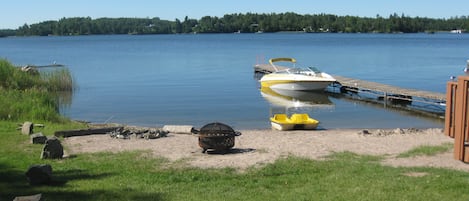 Another view of the beach area showing firepits, dock, and paddle boat.