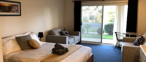 Main room with Queen bed, sitting area with TV, leading out to patio area