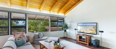 Spacious living area boasting an open-concept design and subtle glimpses of the azure ocean beyond.