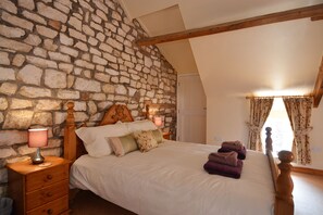 Kingsize bed set against exposed chalk feature wall.