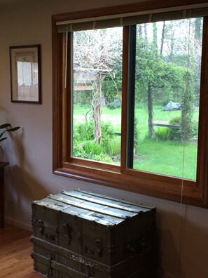 Old chest holds extra sheets, blankets & pillows below large picture window