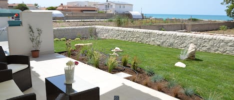 Comoda veranda con vista sul giardino e sul mare. Atmosfera accogliente la sera.