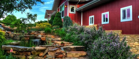 Natural stone steps lead past flowers and a waterfall to the front door.