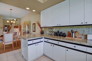 Kitchen to Dining Room view with dimmer lights and ceramic tile floors. 