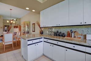 Kitchen to Dining Room view with dimmer lights and ceramic tile floors.