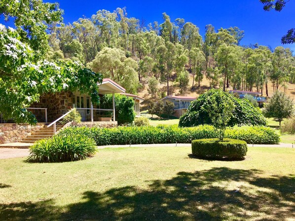 Lodge building with Hilltop villas in the distance. Lush gardens