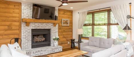 Rustic and Updated living room with neutral colors, gas fireplace, and flat screen tv. Open living and dining space.