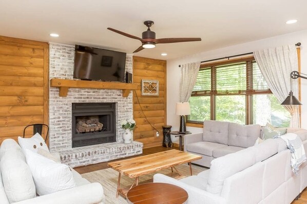 Rustic and Updated living room with neutral colors, gas fireplace, and flat screen tv. Open living and dining space.