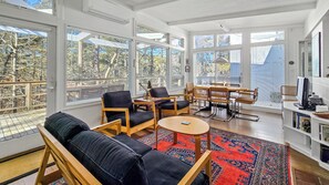 Bright and open living room with vaulted ceiling and door to deck