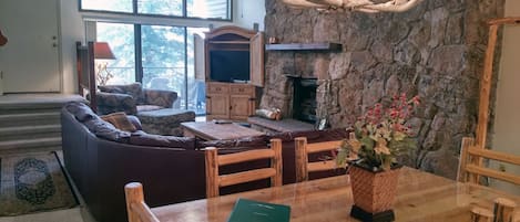 Living room with wood fireplace, dining table, and balcony with gas BBQ