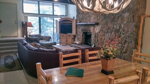 Living room with wood fireplace, dining table, and balcony with gas BBQ