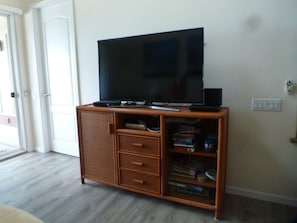 Living room has a big smart TV and a DVD player. 