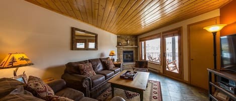 Living Room with wood burning fireplace and balcony looking at the ski resort.