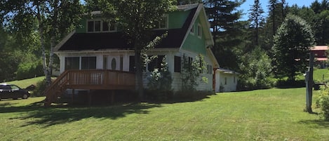 View of front of house, front porch, side yard, driveway to left, garage in back