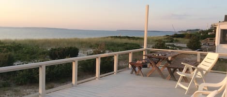 Deck view east. Round cedar table, benches, umbrella, chairs, picnic table