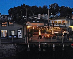 Aerial view of Boathouse to the left, Firepit/eating area with lights, and Main. House to the Right.