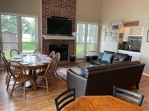 Living/dining area showing TV and bar with windows looking onto side yard.