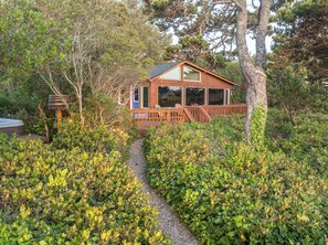 Looking at house from front yard with native salal and shore pines.