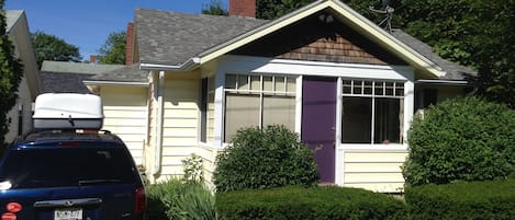 Look for the distinctive purple door! The flower/herb garden are behind the van.