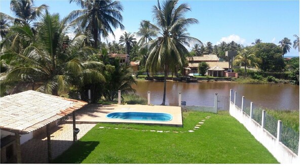 Área verde com piscina, uma pia, churrasqueira, 2 chuveiros.