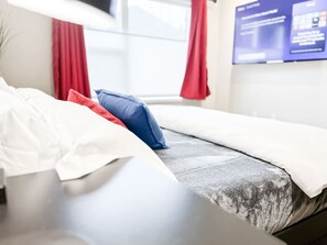 Unwind in the cozy, stylish bedroom featuring soft bedding, colorful accent pillows, and a large flat-screen TV for ultimate relaxation. With plush fabrics and a serene atmosphere, it's the perfect space to recharge