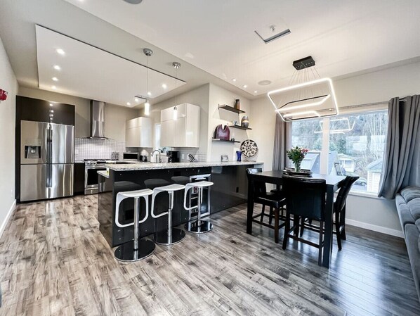 Enjoy both casual and formal dining in this modern space—bar seating for three perfect for morning coffee or a quick bite, alongside an elegant dining table for four, ideal for meals with a view of the city. The sleek kitchen, complete with stainless stee