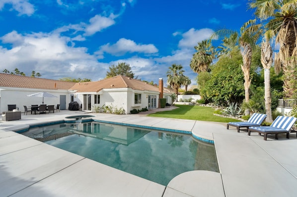 Rear of home with pool & spa and large yard.