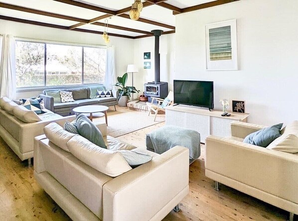 Large downstairs living area with multiple couches, TV and combustion stove