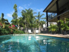 Large swimming pool, set in a tropical garden.