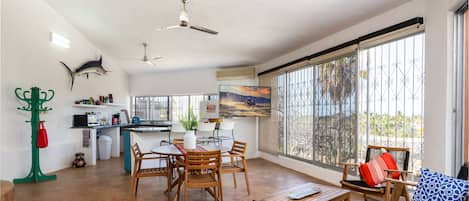 Living room with floor to ceiling windows that offer views to palm trees & ocean