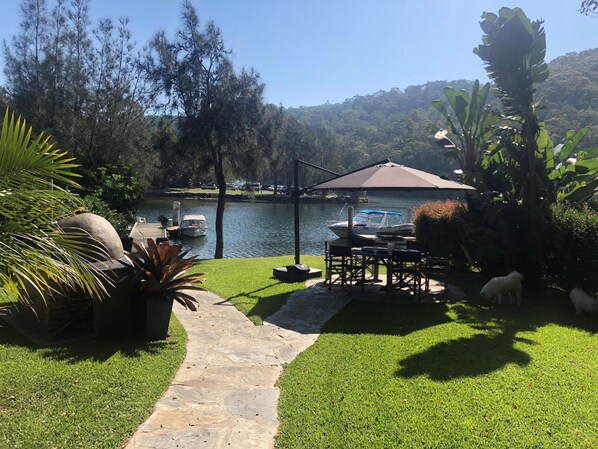 Flat backyard with a jetty, pizza oven and outdoor setting with umbrella