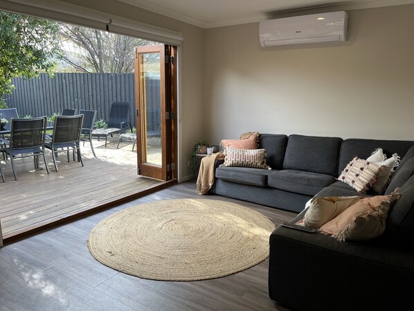 Lounge room with bifold door opening onto outdoor entertaining area.
