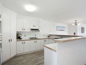 large kitchen with oven, stovetop, microwave, coffee machine and lots of  extras
