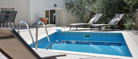 Heated pool, sun chairs, outdoor shower and place to grill.