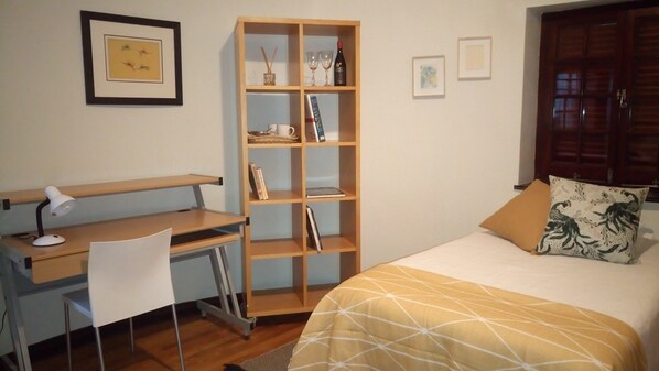 Bedroom containing desk, comfy chair, fridge and microwave.