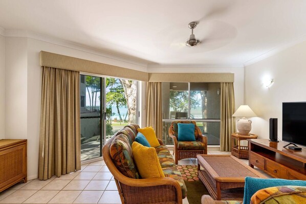 Enjoy the vibrant hues of the living area while staying connected to the outdoors with easy access to the beach just steps away.