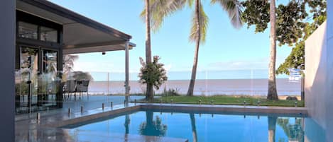 Sparkling salt pool with sea views surrounded by glass pool fence.