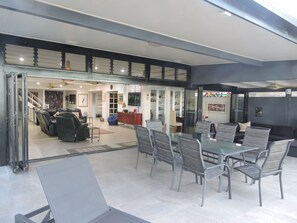 Wall length bi-folds with 8 seat dining table, lounge seating area & weber BBQ.