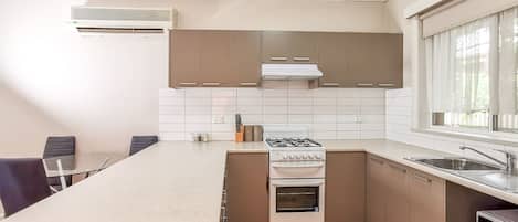 Kitchen with gas stove and cooktop, fridge and microwave.