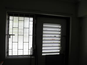 entrance door adjacent to window with burglar bars