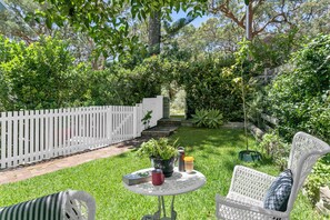 Sunny front garden with seating looks out onto native bush. 