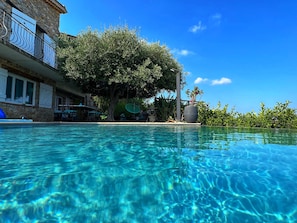 Depuis la piscine vers la terrasse à l’ombre de l’olivier 