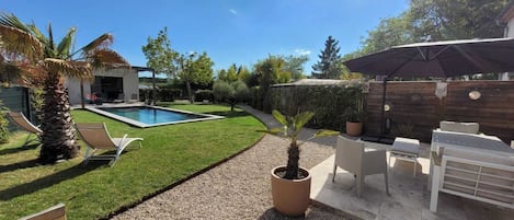 Vue générale du jardin avec le salon extérieur sur la terrasse côté sud