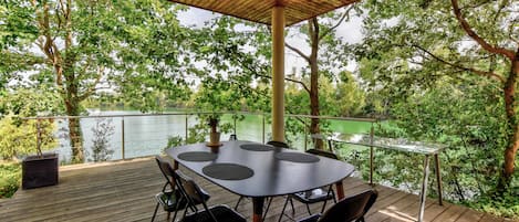 Terrasse ombragée en bois exotique, attenante à la villa, en surplomb du lac