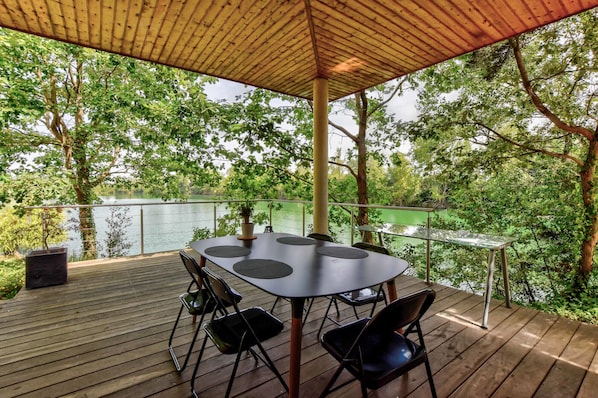 Terrasse ombragée en bois exotique, attenante à la villa, en surplomb du lac