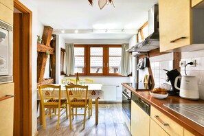 Espace de vie en longueur avec cuisine équipée avec lave-vaisselle et table à manger avec 4 chaises