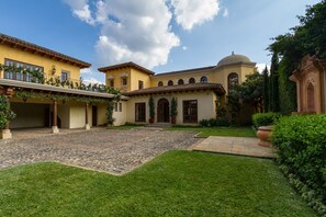 Open gates to front view of main house with fountain and separate garage and gym