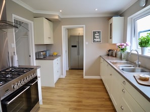 Kitchen with American style fridge freezer in utility room beyond